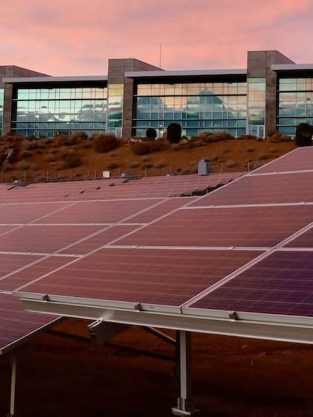 Imagem com painéis solares sob pôr do Sol de cor rosada para exemplificar os benefícios da energia solar para empresas: reduza seus gastos mensais em até 20%