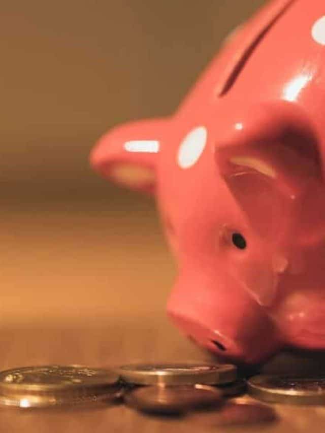 Cofre em formato de porquinho rosa sobre uma mesa de madeira e alguma moeda na frente dele - Descubra como economizar energia elétrica na sua empresa seguindo estas 5 táticas