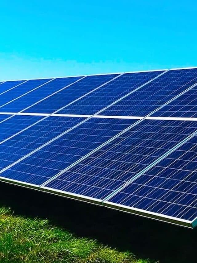 Imagem de um painel solar sob a grama e acima um céu azul para ilustrar usina de placas solares: o que é, como funcionam e por que são importantes para economia do país (e da sua)