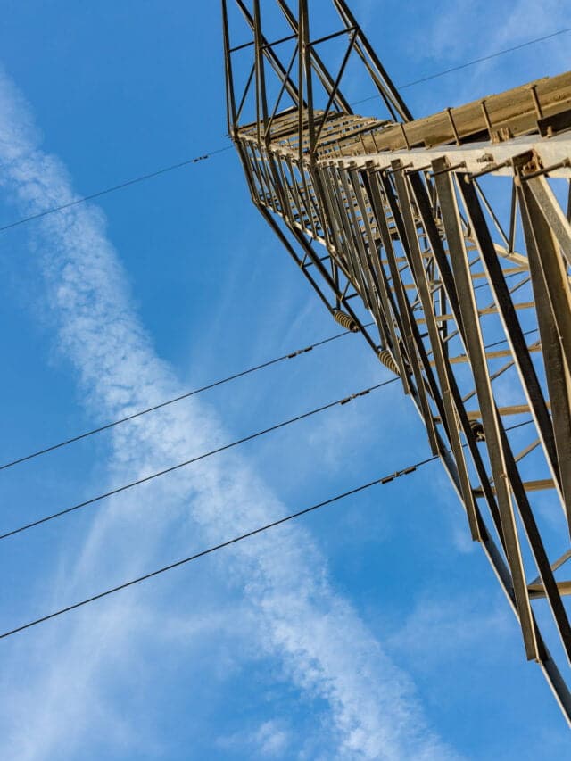 Electricity transmission towers or pylons with cloudy sky on the background