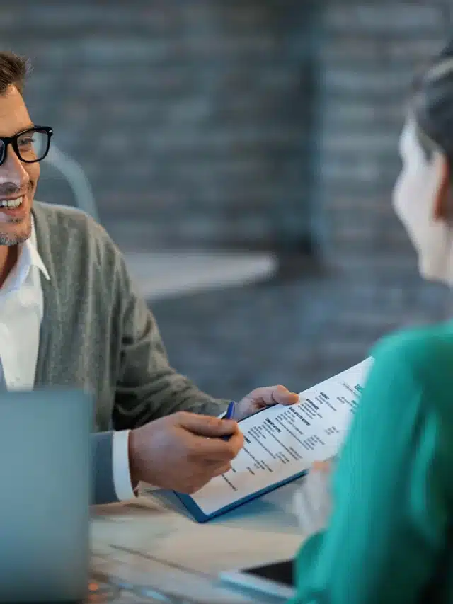 happy-businessman-talking-his-colleague-while-going-through-financial-reports-office copiar