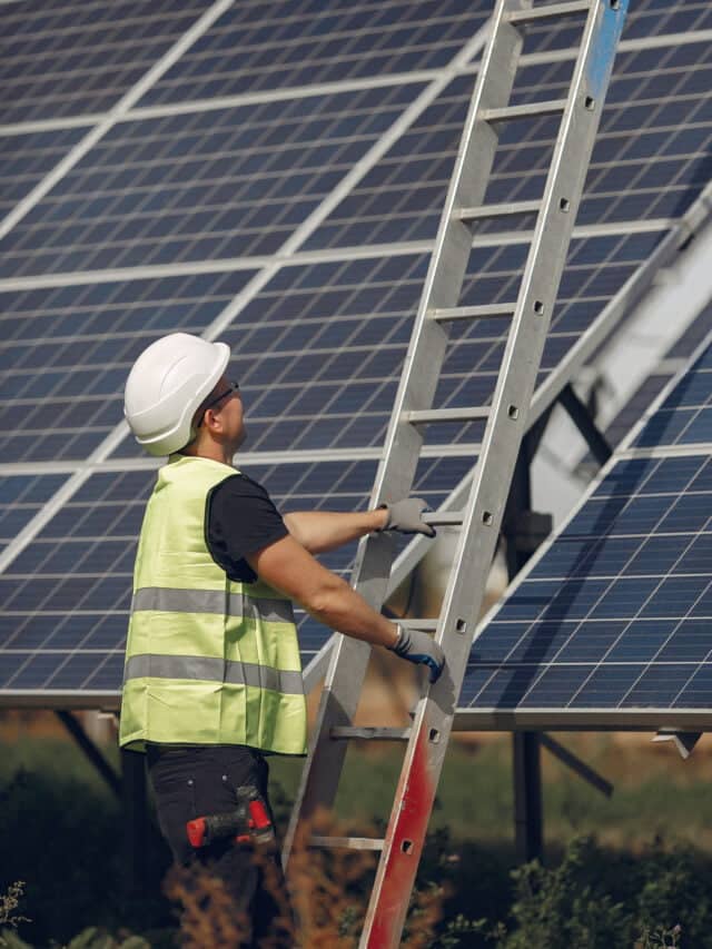 Man in a white helmet near a solar panel