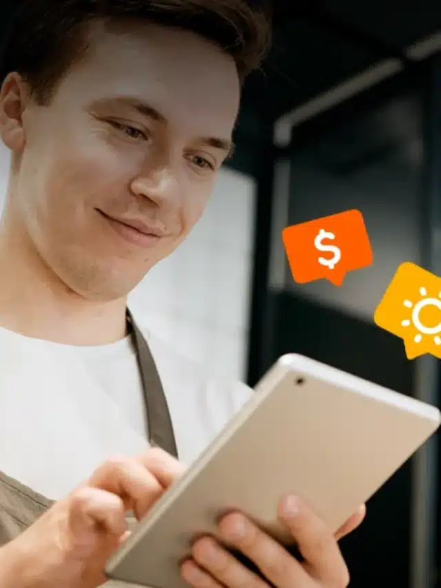 Rapaz de avental, segurando um tablet e acima do aparelho tem dois ícones (cifrão e Sol) laranja e amarelo para exemplificar artigo sobre Será que a contratação de energia solar por assinatura vale a pena? Descubra aqui