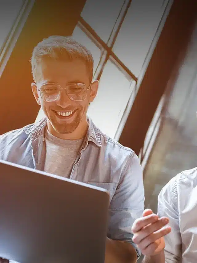 Dois homens jovens sorrindo ao segurar um painel para exemplificar artigo sobre Como utilizar a energia solar para reduzir a conta de luz