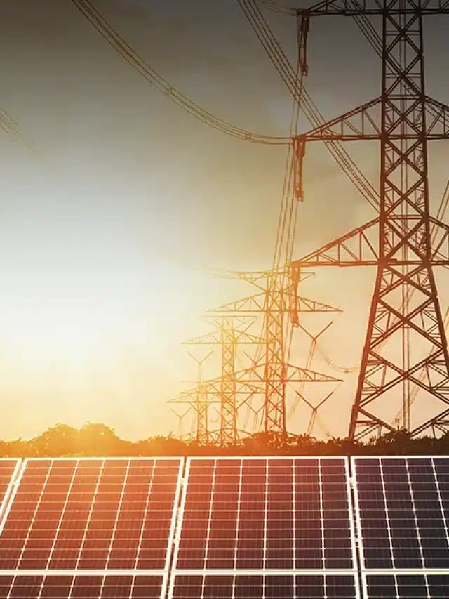 Na imagem, na parte inferior tem paneis solares e acima, cinco torres de linhas de transmissão de energia para artigo sobre Qual a diferença entre o sistema on-grid e off-grid