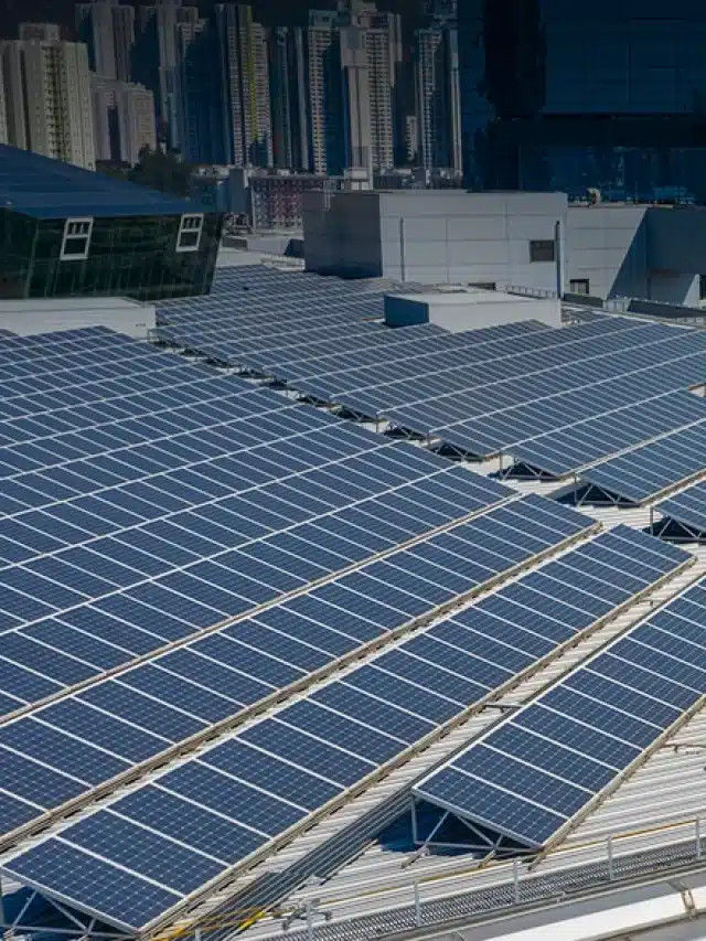 Telhado de prédio com painéis solares e ao fundo vários prédios para artigo de Como ter energia solar sem precisar comprar painéis solares