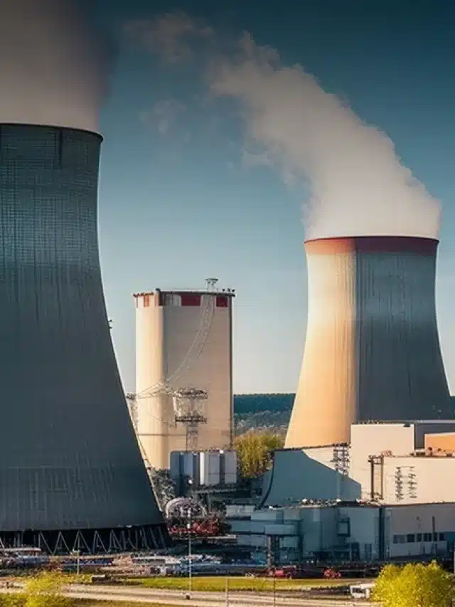 Na imagem duas chaminés, um reservatório e três torres de transmissão e atrás um céu azul para exemplificar artigo sobre Energia nuclear é sustentável? Saiba aqui