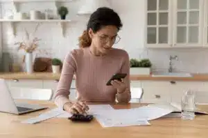 Mulher fazendo conta na calculadora para artigo ICMS na conta de luz