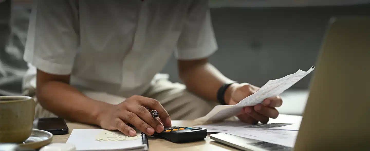 Homem fazendo conta na calculadora para artigo É obrigatório pagar o ICMS cobrado na conta de luz?