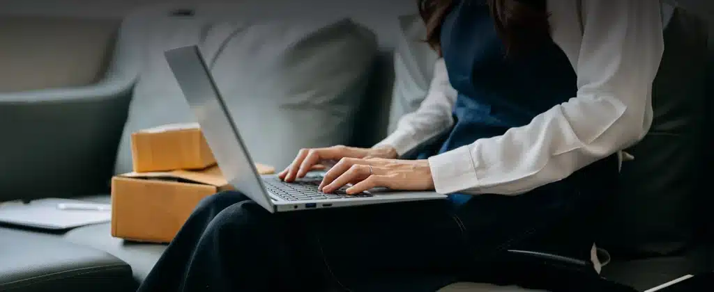 Mulher digitando com laptop no colo para artigo Conheça a plataforma de gestão de energia da Sunne