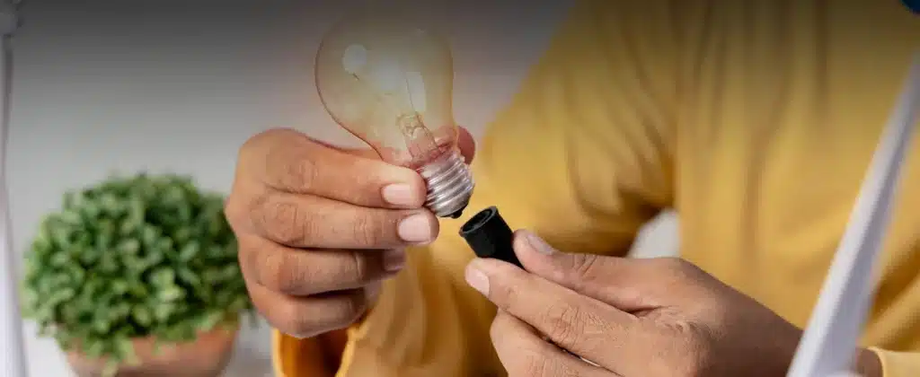 Pessoa segurando lâmpada acesa para Qual a importância de investir em energia fotovoltaica?