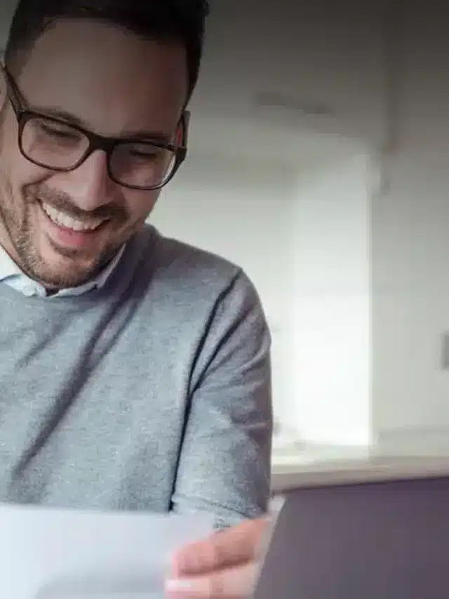 Homem jovem sorrindo segurando conta para As vantagens de ter energia solar na sua empresa
