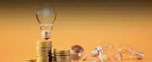 Lâmpadas e moedas no fundo laranja para Entenda tudo sobre imposto na conta de luz