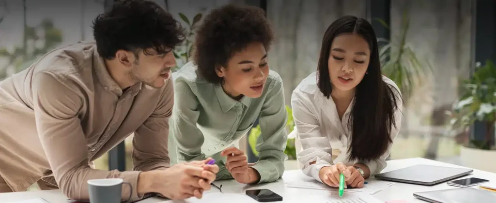 Jovens analisando projetos sobre mesa para O papel da política de educação ambiental nas empresas