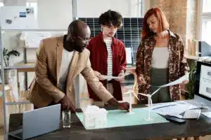 Profissionais analisando projetos de energia renovável em um escritório, destacando os benefícios ambientais da energia por assinatura.