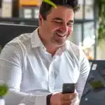 Um homem está sentado feliz com a em uma mesa com a energia por assinatura contratada