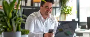 Um homem está sentado feliz com a em uma mesa com a energia por assinatura contratada