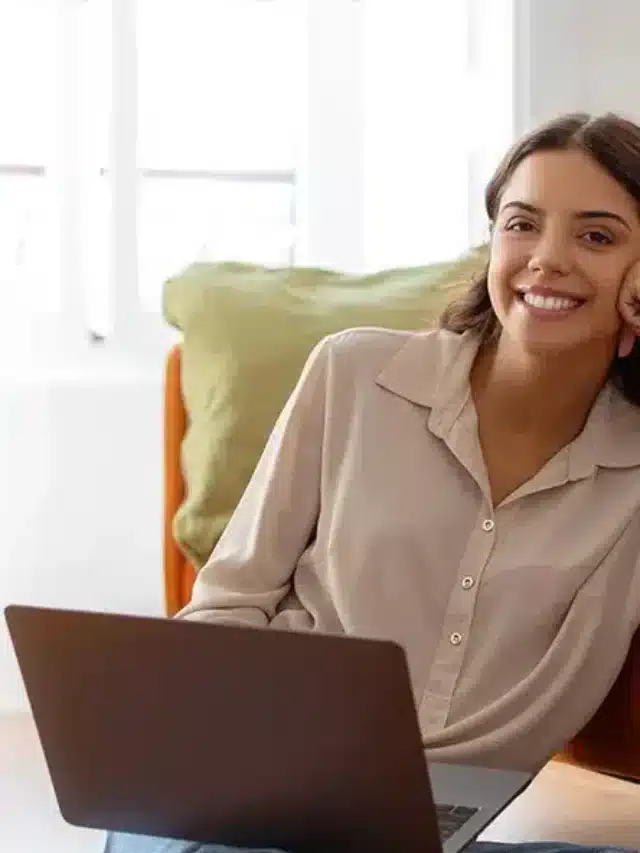 Jovem moça alegre trabalhando em seu laptop agora que economiza com energia solar por assinatura