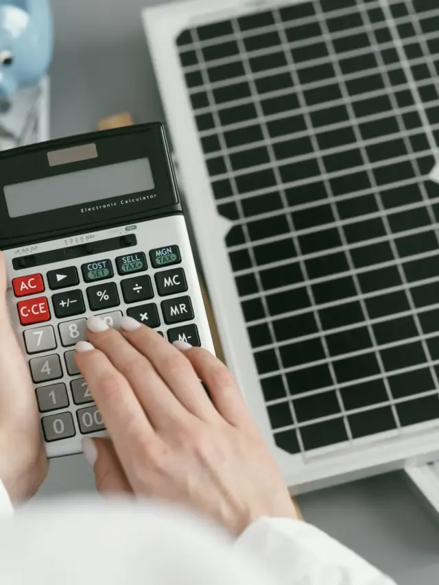 Pessoa calculando custos ao lado de painéis solares, simbolizando o investimento em uma micro usina solar e o retorno financeiro com energia limpa.