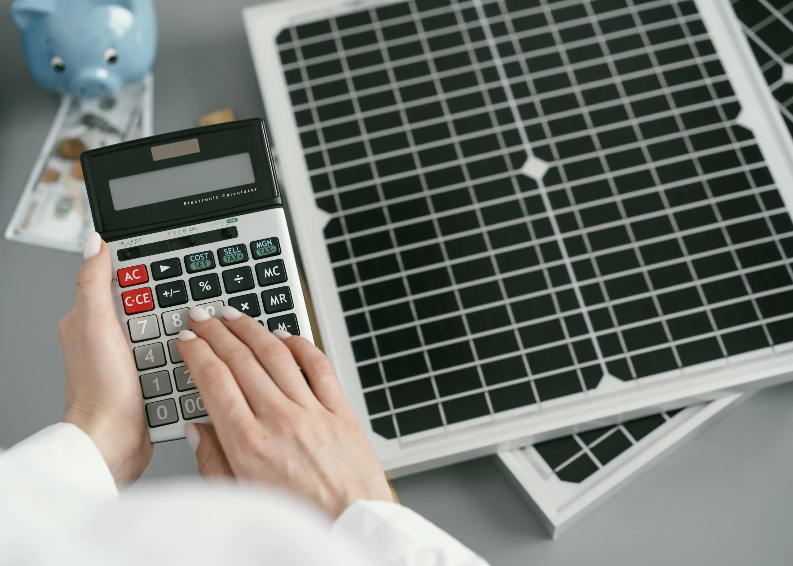 Pessoa calculando custos ao lado de painéis solares, simbolizando o investimento em uma micro usina solar e o retorno financeiro com energia limpa.