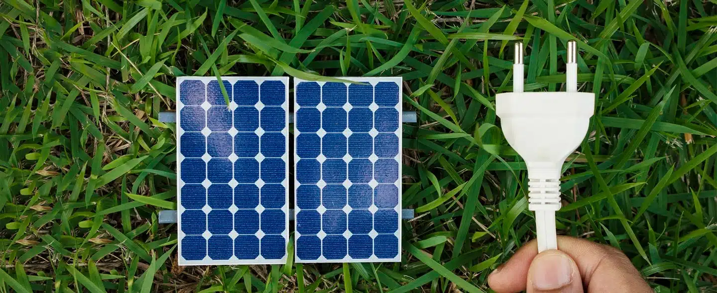 Segurando um fio ao lado de um painel fotovoltaico no fundo da grama para energia solar sem placa