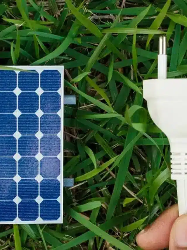 Segurando um fio ao lado de um painel fotovoltaico no fundo da grama para energia solar sem placa