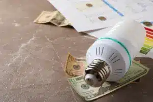 Close-up de uma lâmpada e cédulas de dinheiro para exemplificar artigo sobre energia por assinatura.