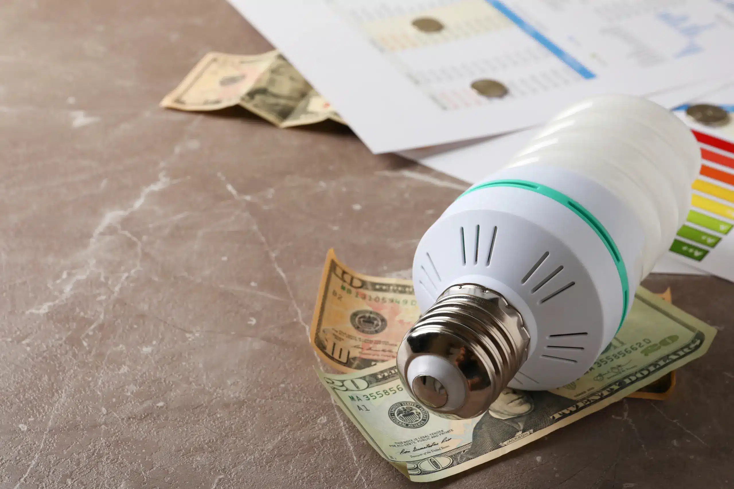 Close-up de uma lâmpada e cédulas de dinheiro para exemplificar artigo sobre energia por assinatura.