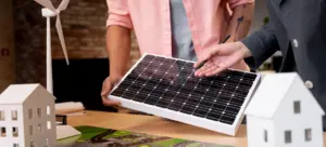 Duas pessoas analisando um painel solar em maquete de projeto, representando o conceito de o que é geração distribuída e como funciona na prática.