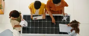 Parcerias estratégicas em energia solar representadas por um grupo de pessoas analisando um painel solar em ambiente profissional.