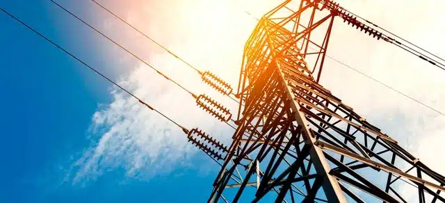 Torre de transmissão de energia elétrica com céu azul ao fundo, representando a infraestrutura compartilhada entre mercado livre x mercado cativo no Brasil.