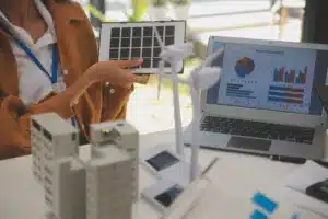 Simulação de projeto de energia com painel solar e turbinas eólicas em maquete, ilustrando análise comparativa entre geração distribuída ou mercado livre para empresas.
