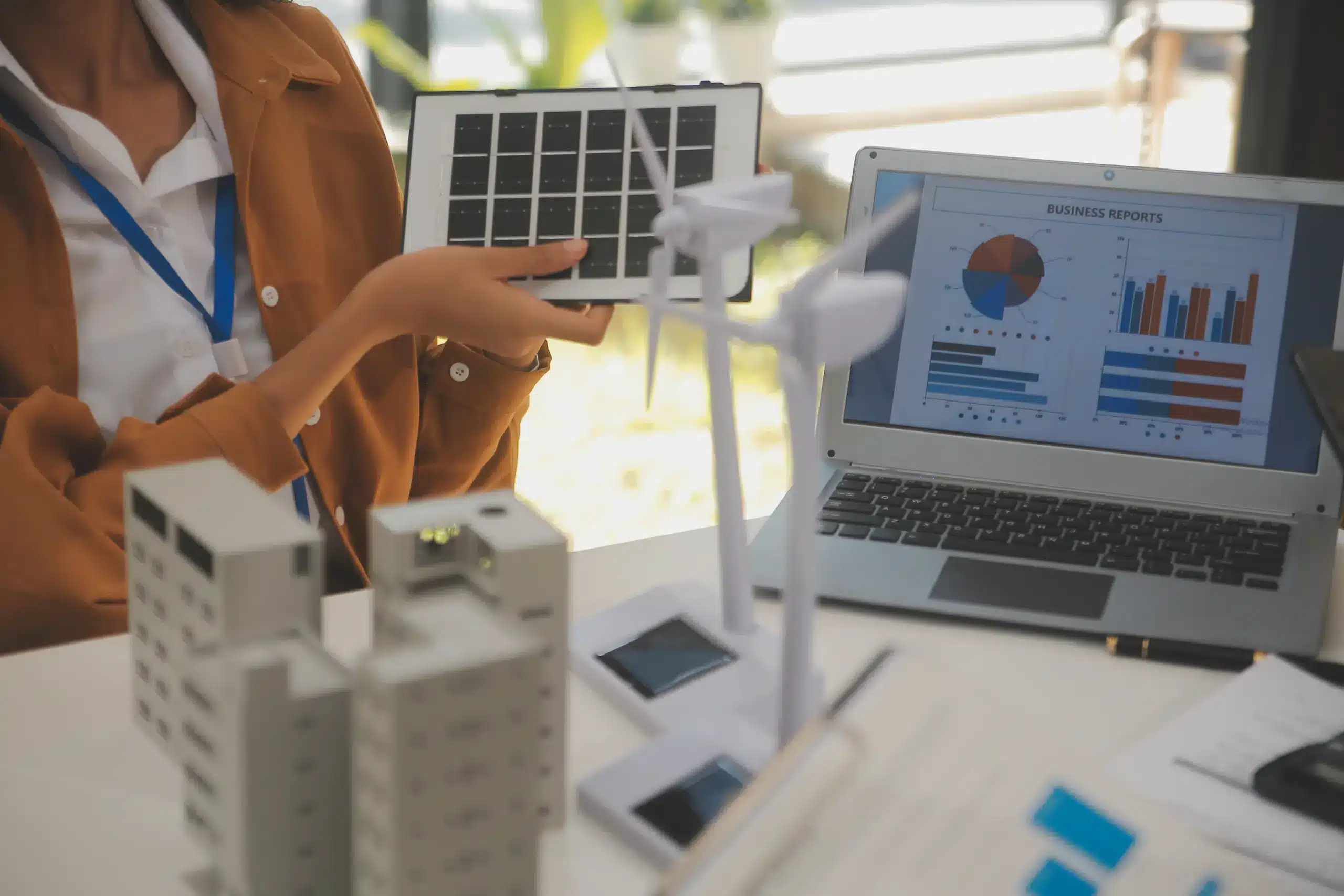 Simulação de projeto de energia com painel solar e turbinas eólicas em maquete, ilustrando análise comparativa entre geração distribuída ou mercado livre para empresas.