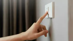 Pessoa desligando o interruptor, representando redução de consumo e dúvidas sobre o funcionamento da energia por assinatura.