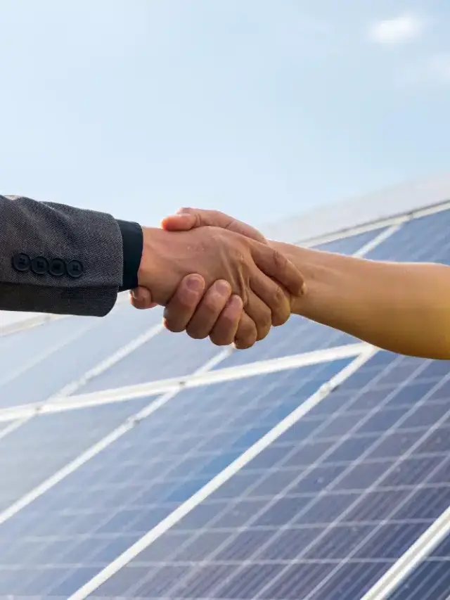 duas-pessoas-apertando-as-maos-contra-painel-solar-apos-conclusao-acordo-na-area-de-energias-renovaveis 1