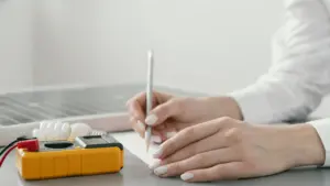 Pessoa escrevendo em papel ao lado de um painel solar e equipamentos de medição, simbolizando planejamento e gestão em energia por assinatura.