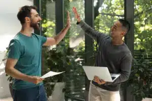 Dois profissionais comemorando parceria de sucesso, simbolizando estratégias colaborativas para captação de consumidores em energia solar.