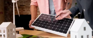 Duas pessoas analisando um painel solar em maquete de projeto, representando o conceito de o que é geração distribuída e como funciona na prática.