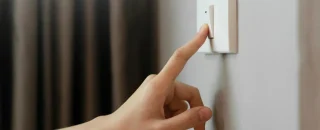 Pessoa desligando o interruptor, representando redução de consumo e dúvidas sobre o funcionamento da energia por assinatura.