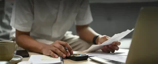 Homem fazendo conta na calculadora para artigo É obrigatório pagar o ICMS cobrado na conta de luz?