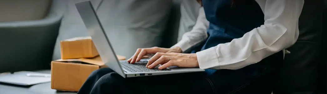 Mulher digitando com laptop no colo para artigo Conheça a plataforma de gestão de energia da Sunne