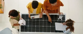 Parcerias estratégicas em energia solar representadas por um grupo de pessoas analisando um painel solar em ambiente profissional.
