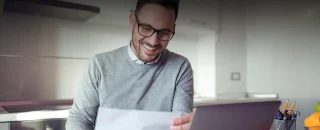 Homem jovem sorrindo segurando conta para As vantagens de ter energia solar na sua empresa