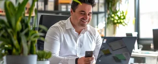 Um homem está sentado feliz com a em uma mesa com a energia por assinatura contratada