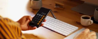 Mão segurando um celular para o artigo Benefícios tributários de energia solar para sua empresa