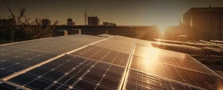 Placas solares em cima de um telhado, ao fundo tem o telhado de alguns prédios e o pôr do Sol ao fundo para exemplificar o artigo sobre as 5 principais características da energia solar para você conhecer