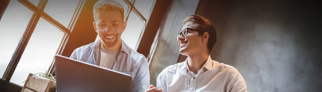 Dois homens jovens sorrindo ao segurar um painel para exemplificar artigo sobre Como utilizar a energia solar para reduzir a conta de luz