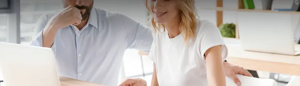 Homem e mulher com roupa branca em frente um laptop branco enquanto usam e olhem uma prancheta com atenção para artigo de 5 formas de economizar energia