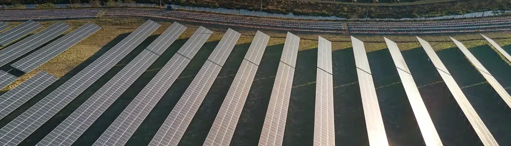 Terreno aberto completamente cheio de placas solares inclinadas para exemplificar artigo de Como funciona usinas fotovoltaicas e quais seus impactos