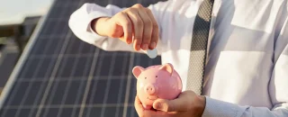 Gestão de inadimplência em energia solar representada por uma usina solar ao fundo e a mão de um investidor colocando dinheiro em um cofrinho de porquinho, simbolizando segurança financeira e retorno de investimento.